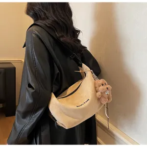 Vue détaillée d'un sac bandoulière beige en daim avec un joli pendentif ours en peluche
