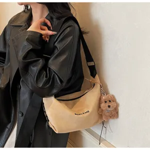 Détail d'un sac bandoulière en daim beige avec broderie et charm d'ours mignon