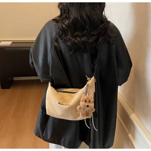 Détail d'un sac à bandoulière beige rétro mat avec un charmant porte-clés ours en peluche.