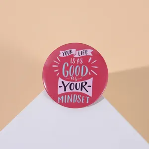 Close-up of red tinplate badge with inspirational quote 'Your life is as good as your mindset'