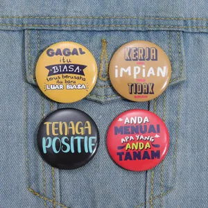 Close-up of four colorful tinplate badges with inspirational quotes on denim jacket