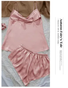 Elegant pink ice silk pajama set featuring camisole and shorts on lace background