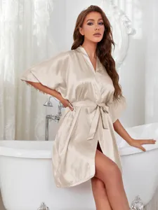 Close-up of elegant champagne silk satin robe worn by a model in a luxury bathroom