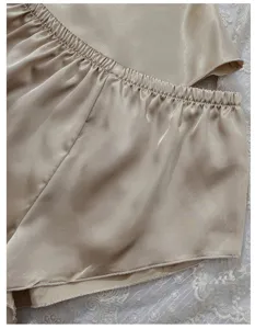 Detail view showing smooth texture of champagne silk pajama shorts with elastic waistband