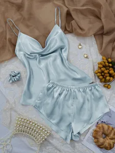 Close-up detail of light blue satin pajama set with camisole and shorts on white lace