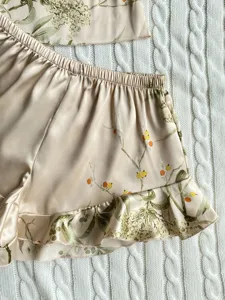 Close-up detail of floral print faux silk pajama shorts featuring a ruffled hem