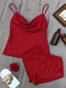 Detailed view of red silk-like pajama camisole and shorts set on grey background