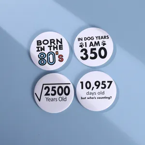 Détail de pins en fer-blanc avec des designs humoristiques sur les maths et l'âge
