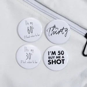 Gros plan de quatre badges ronds en fer blanc avec des citations d'anniversaire drôles.