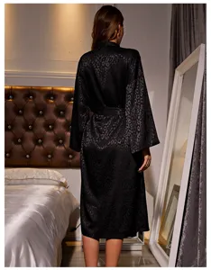 Detailed back view of an elegant black leopard print satin robe in a cozy bedroom setting