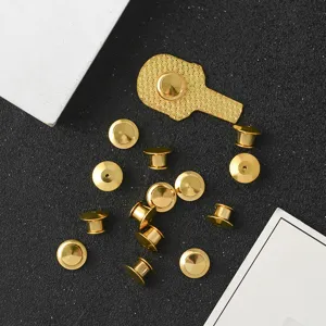 Detailed macro view of gold-colored zinc alloy brooch pin backs on black background