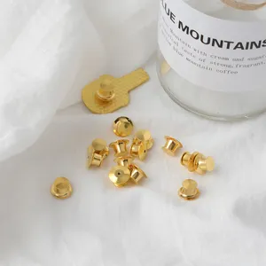 Close-up of golden metal butterfly clutch pin backs on white fabric