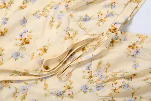 Close-up detail of the elegant yellow floral print fabric and waist strap of the dress.