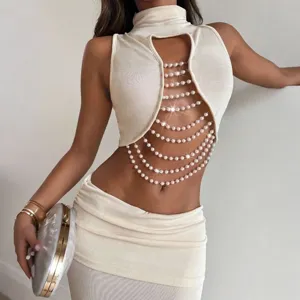 Detail shot of a stylish women's slim mock neck sleeveless hollow pearl chain top and skirt.