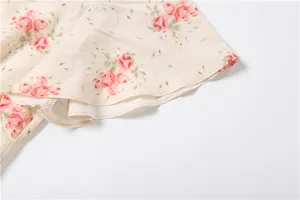 Exquisite floral print dress detail showcasing delicate pink roses on premium beige fabric.