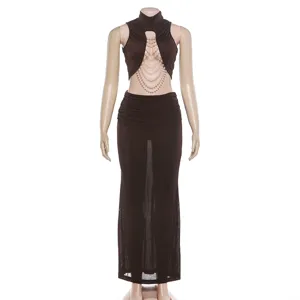 Detailed view of the slim mock neck sleeveless cutout pearl chain tank top and low waist maxi skirt.