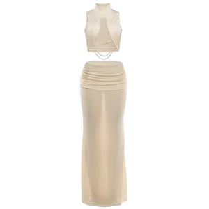 Beige sleeveless crop top with cutout and pearl chain, paired with a stylish low-waist maxi skirt.