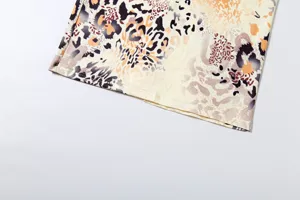 Detailed view of the stylish irregular abstract print dress fabric showing fine hem stitching.