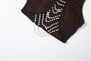 Close-up detail of dark brown sleeveless vest featuring elegant layered pearl chains.