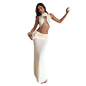 Stylish women's beige halter crop top with pearl chains and matching low waist maxi skirt set.