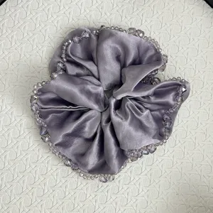 Detailed macro view of a luxury grey satin scrunchie with sparkling crystal bead edging