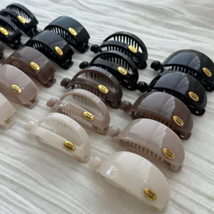 Reihe verschiedener minimalistischer Bananen-Haarklammern in Neutraltönen auf weißem Stoff