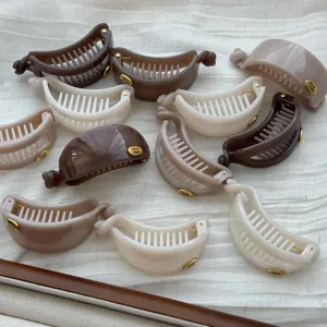 Detaillierte Nahaufnahme minimalistischer Bananen-Haarspangen in neutralen Tönen auf Stoff