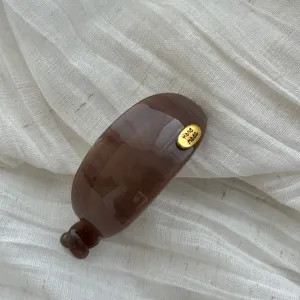 Detailansicht einer großen braunen ovalen Bananen-Haarspange mit goldenem Hand Made-Tag