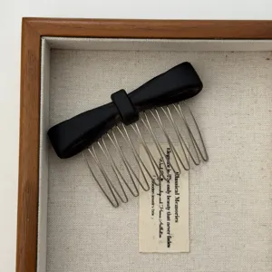 High-definition close-up of a minimalist matte black bow hair comb with silver teeth.