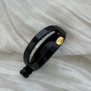 Detailansicht der schwarzen ovalen Haarspange mit goldenem Hand Made Etikett