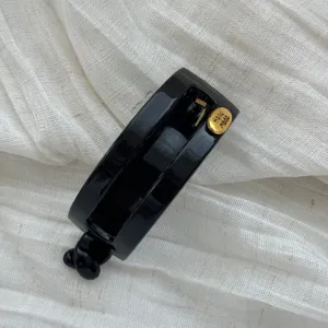 Nahaufnahme einer eleganten glänzend schwarzen ovalen Haarklammer mit Goldetikett