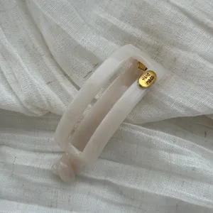 Detailansicht einer eleganten cremefarbenen ovalen Haarklammer mit goldenem Hand Made Tag