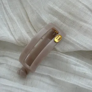 Detail der beigen Haarspange mit 'Hand Made' Goldanhänger auf Stoff.
