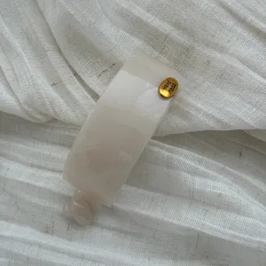 Detailansicht der eleganten creme-acetat Haarklammer mit goldenem Handmade-Etikett.