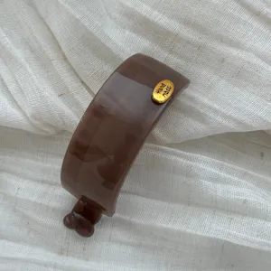 Nahaufnahme einer eleganten braunen Haarklammer mit goldenem Hand Made Emblem
