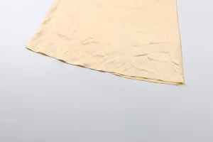 Detail view of the elegant satin dress hem in champagne color, showing smooth fabric texture.