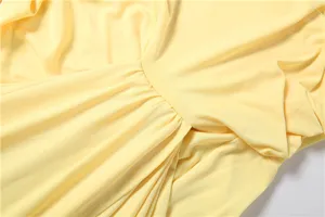 Detailansicht des gelben figurbetonten Kleides mit elegantem Faltenwurf und feinen Nähten.