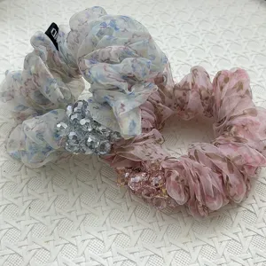 Makro-Detail von Organza-Haargummis mit eleganten Blumenmustern und Kristallperlen