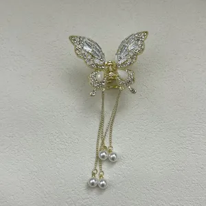 Detailed view of gold butterfly hair claw clip with crystal inlay and pearl tassels