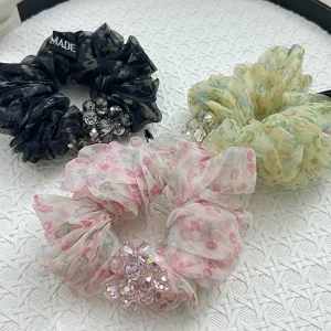 Nahaufnahme von drei Organza-Haargummis mit Blumenmuster, Leopardenprint und Kristallen.