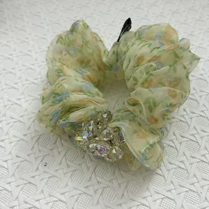 Detailansicht eines geblümten Organza-Haargummis mit schillernden Kristallperlen.
