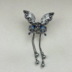 Close-up of elegant metal butterfly claw clip with blue crystals and hanging tassels