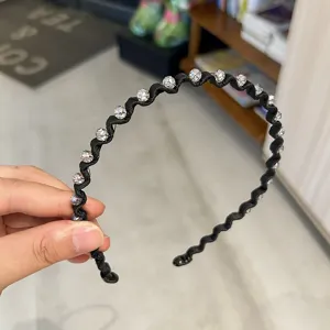 Close-up of elegant black wavy headband with sparkling crystal embellishments