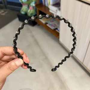 Detail view of stylish wavy black headband decorated with clear sparkling crystals