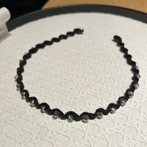 Close-up of elegant black wavy headband decorated with faceted grey crystal beads