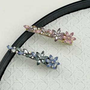 Detailed macro view of two elegant crystal floral hair clips in pink and blue hues
