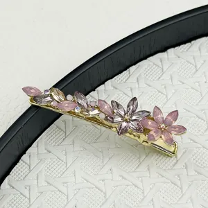 Close-up of sparkling crystal flower hair clip with pink and champagne stones.