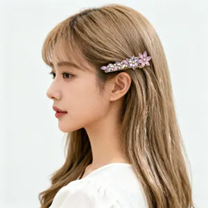 Detail side view of a sweet crystal flower hair clip with purple zircons on model