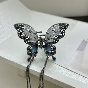 Detailed view of a metal butterfly hair claw clip with blue crystals and long tassels.