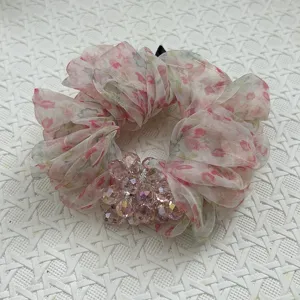 Detailansicht eines rosa geblümten Organza-Scrunchies mit facettierten Kristallperlen